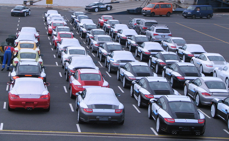 Gereihte Autos in Schutzfolie, die für den Transport von einem Mitarbeiter kontrolliert werden