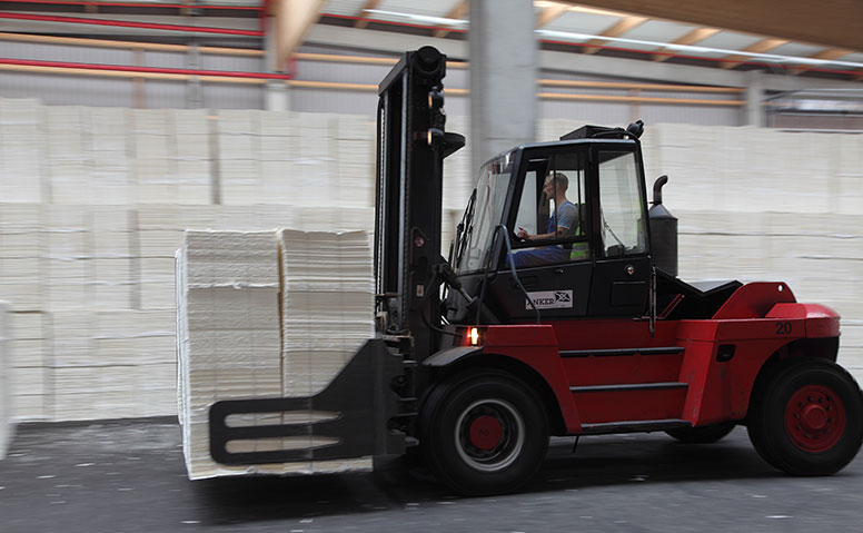 Forstprodukte: Roter Gabelstapler transportiert Forstprodukte in einer Lagerhalle 