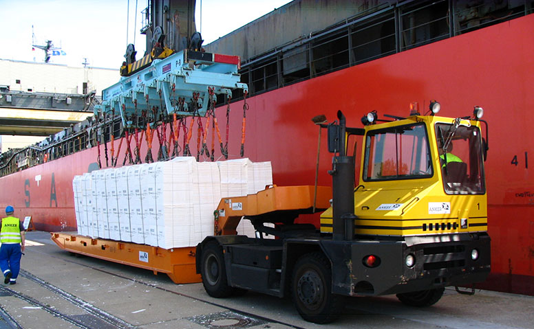 Forstprodukte: Großes Frachtschiff bei der Entladung von Forstprodukten auf eine Zugmaschine für den Transport zur Zwischenlagerung in die Halle 