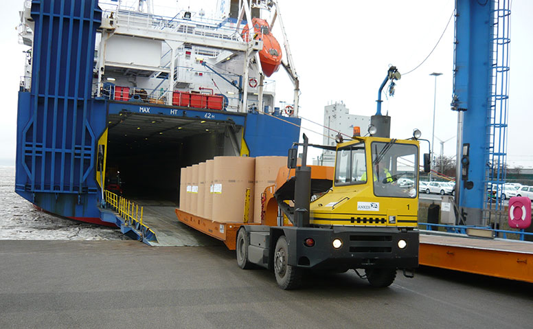 Forstprodukte: Ein blaues Transportschiff bei der Entladung von Forstprodukten auf eine Zugmaschine am Forstproduktenterminal in Emden
