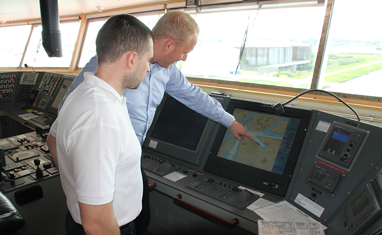 Ships Agency: Eine Person erklärt einer anderen Perosn in der Kommandobrücke die Route auf einem Monitor