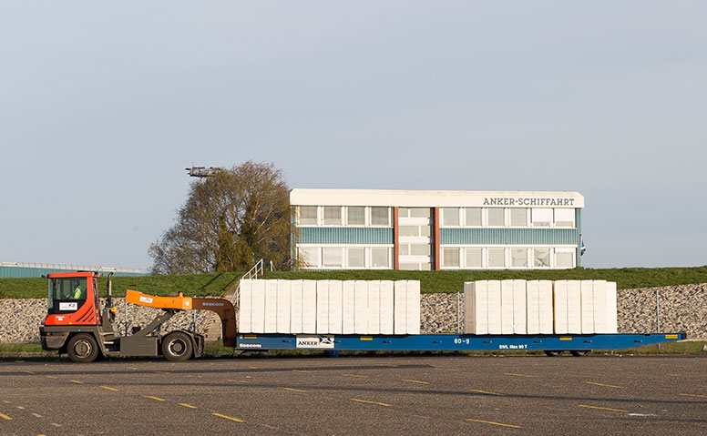 Forstprodukte: Zugmaschine, die Forstprodukte transportiert. Im Hintergrund ist das Gebäude der Anker Schiffahrt zu sehen