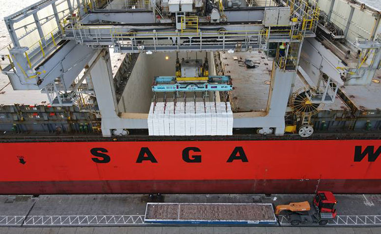 Handling of Forest Products: A large red SAGA cargo ship unloads forestry products onto a tractor at the forestry product terminal in Emden