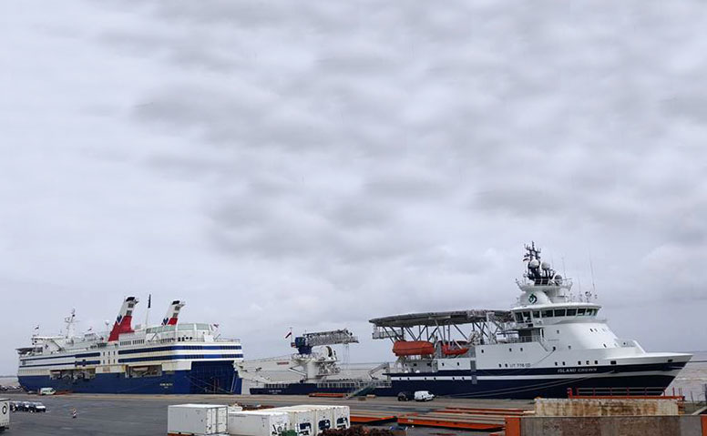 Ships Agency: Über zwei hintereinander liegenden weiß-blauen Schiffen an der Pier am Emder Hafen sieht man einen wolkigen Himmel